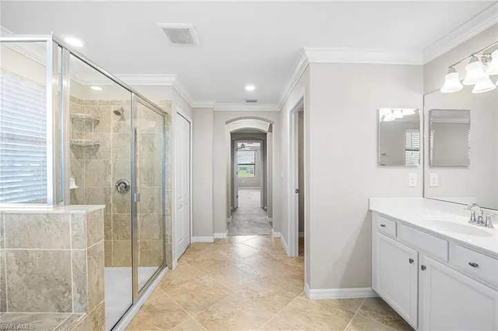Bathroom with a shower with door, vanity, and a wealth of natural light