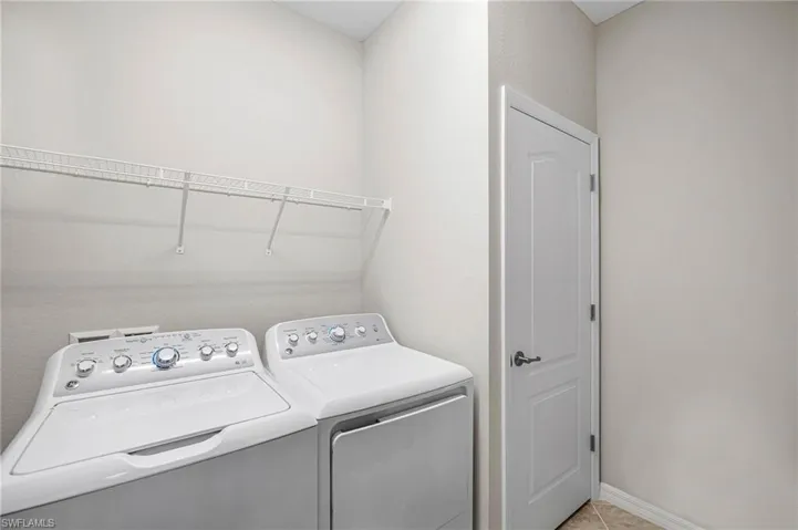 Washroom with light tile patterned floors and washer and clothes dryer