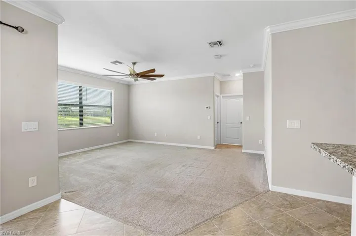 Carpeted spare room with ceiling fan and ornamental molding