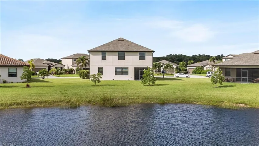 Back of house with a yard, a water view, and a sunroom