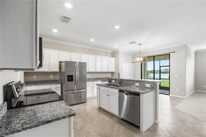 Kitchen featuring stone countertops, appliances with stainless steel finishes, a kitchen island with sink, sink, and white cabinets