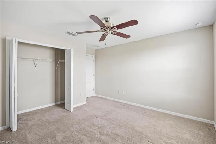 Unfurnished bedroom featuring light carpet, ceiling fan, and a closet