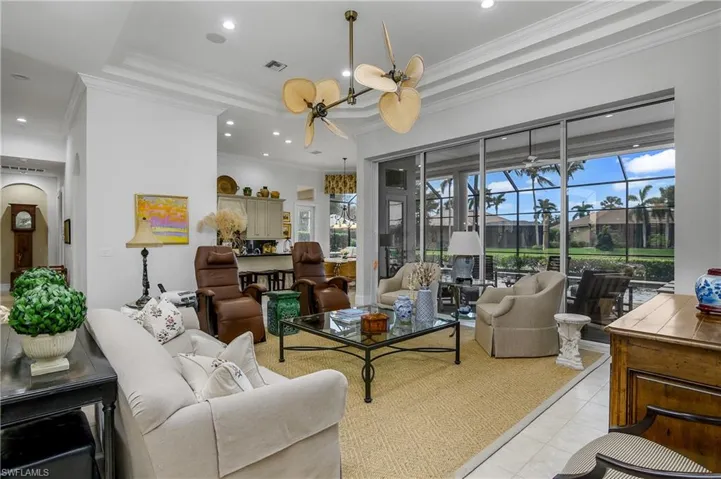 Tiled living room featuring an inviting chandelier, ornamental molding, and a raised ceiling