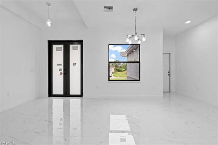 Empty room featuring light marble finish floors, a chandelier, and recessed lighting