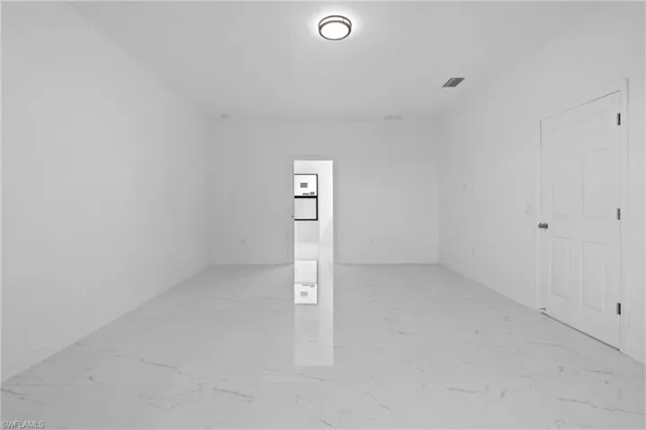 Spare room featuring light marble finish floors and baseboards