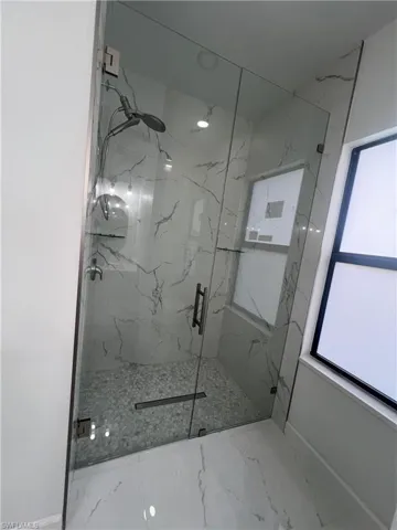 Bathroom with a marble finish shower and marble finish floors