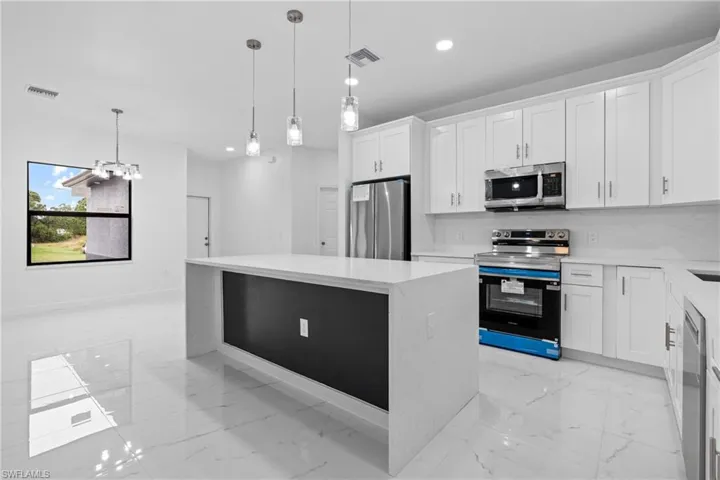 Kitchen with a kitchen island, light marble finish flooring, decorative backsplash, appliances with stainless steel finishes, and recessed lighting