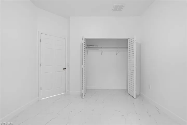Unfurnished bedroom with light marble finish flooring and a closet