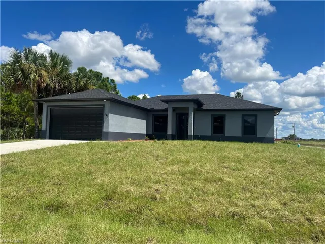 View of front of home with a front yard, driveway, a garage, and stucco siding