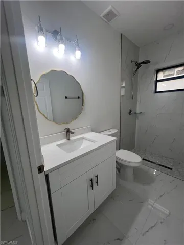 Bathroom with vanity, marble finish floors, and a marble finish shower