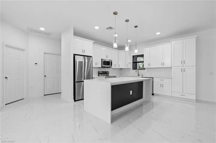 Kitchen with a kitchen island, light marble finish floors, stainless steel appliances, pendant lighting, and white cabinetry
