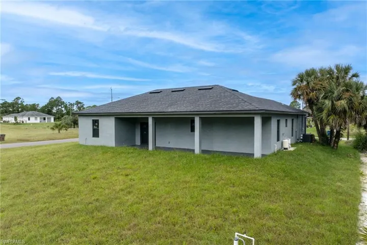 Back of property with a yard, stucco siding, and a shingled roof