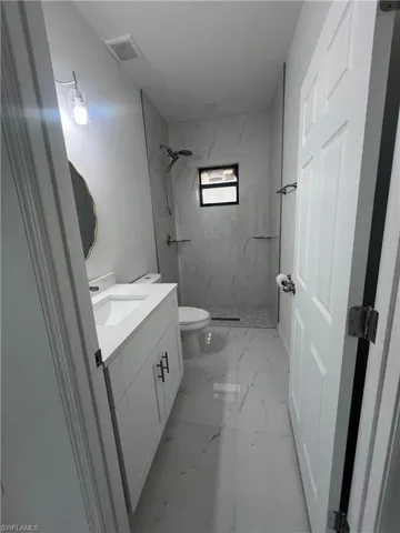 Bathroom featuring a marble finish shower, vanity, and light marble finish floors