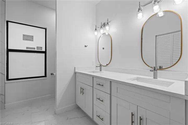 Full bath with light marble finish flooring and double vanity