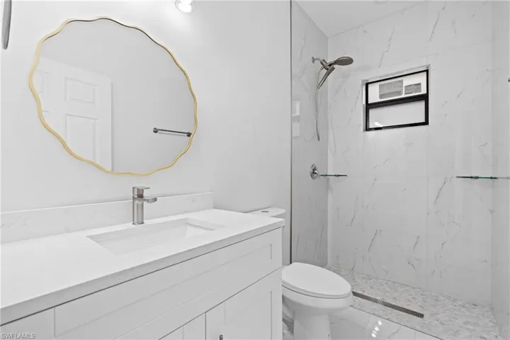 Bathroom with vanity and a marble finish shower