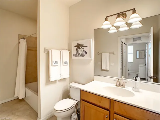 Bathroom featuring vanity, shower / bathtub combination with curtain, and light tile patterned floors