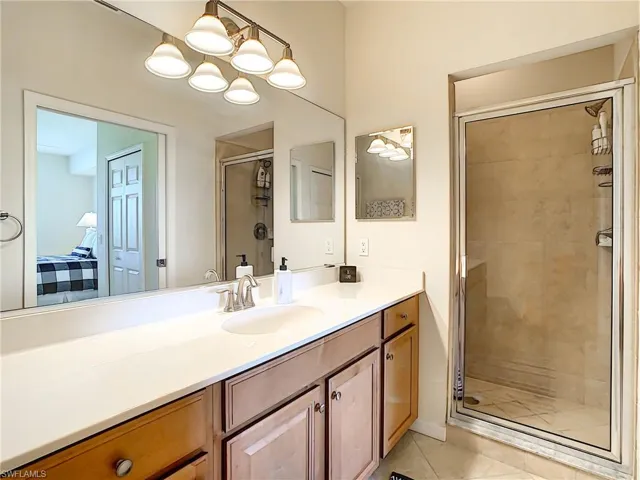 Ensuite bathroom featuring a stall shower, light tile patterned floors, and vanity
