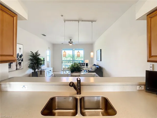 Kitchen with light countertops, track lighting, brown cabinets, and ceiling fan