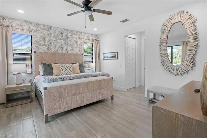 Bedroom featuring wood tiled floors, multiple windows, a ceiling fan, wallpapered walls, and recessed lighting