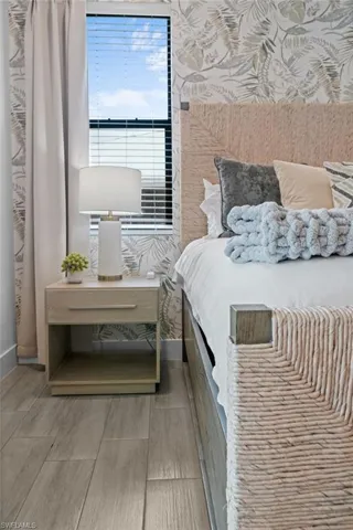 Bedroom with wallpapered walls and wood tiled floors