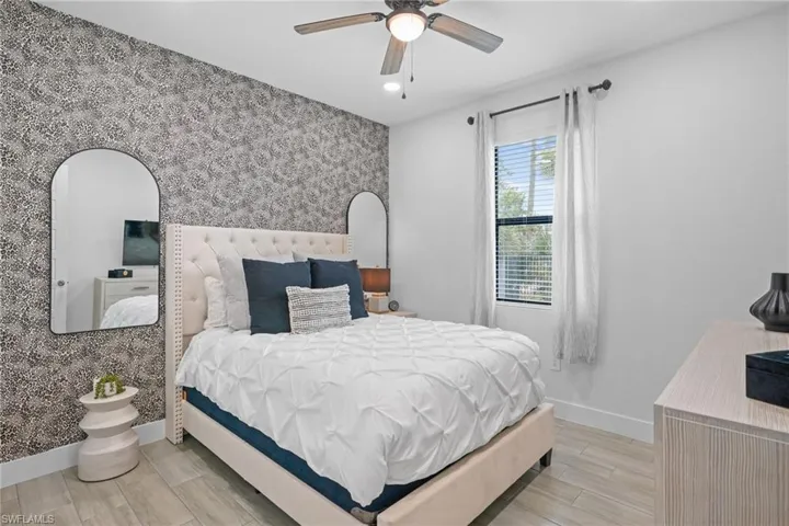 Bedroom featuring wood finish floors, wallpapered walls, a ceiling fan, recessed lighting, and an accent wall