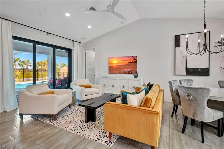 Living area with vaulted ceiling, recessed lighting, a ceiling fan, wood finish floors, and a chandelier
