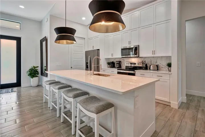 Kitchen featuring white cabinetry, light stone counters, a breakfast bar area, wood tiled floors, and recessed lighting