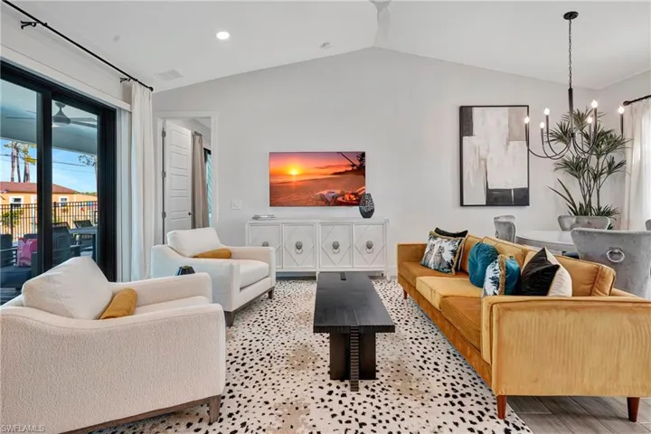Living room featuring vaulted ceiling, a chandelier, and recessed lighting