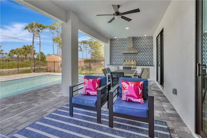 Fenced backyard featuring an outdoor kitchen, a patio area, and a ceiling fan