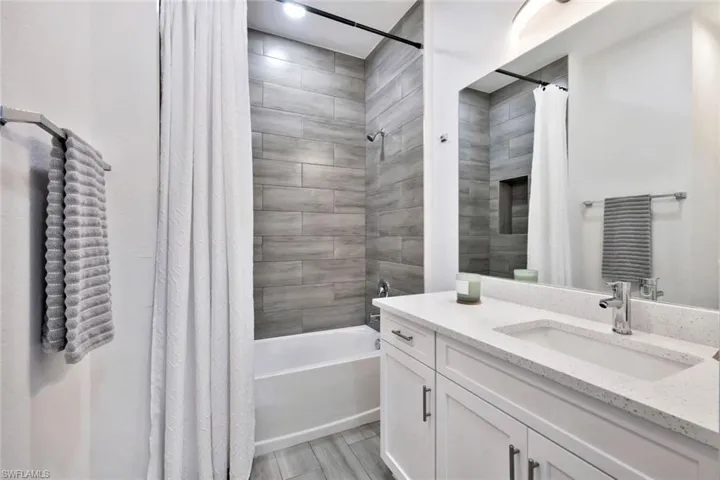 Bathroom featuring shower / bathtub combination with curtain, vanity, and wood tiled floors