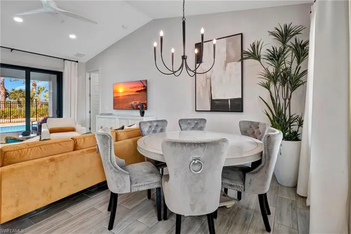 Dining space featuring wood tiled floors, lofted ceiling, a chandelier, recessed lighting, and ceiling fan