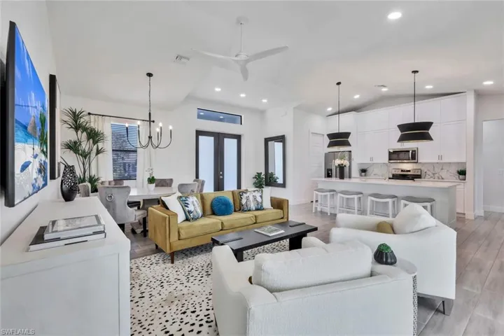 Living area with a chandelier, ceiling fan, vaulted ceiling, recessed lighting, and light wood-type flooring