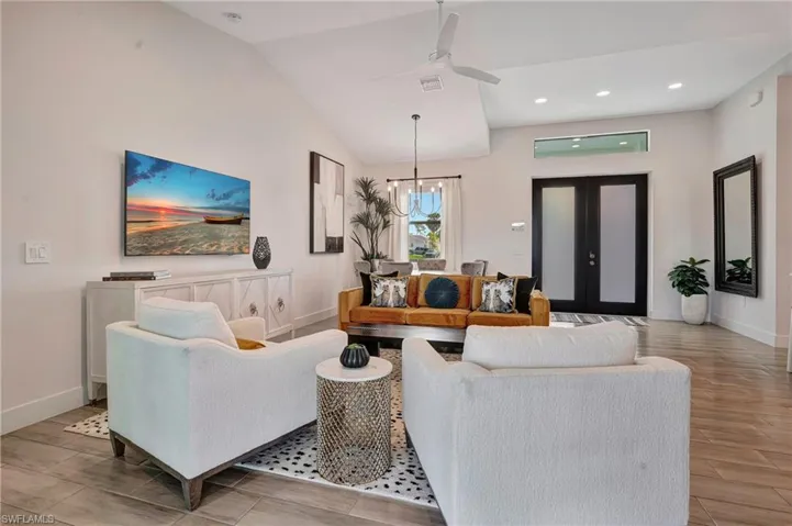 Living area featuring wood tiled floors, vaulted ceiling, ceiling fan, recessed lighting, and french doors