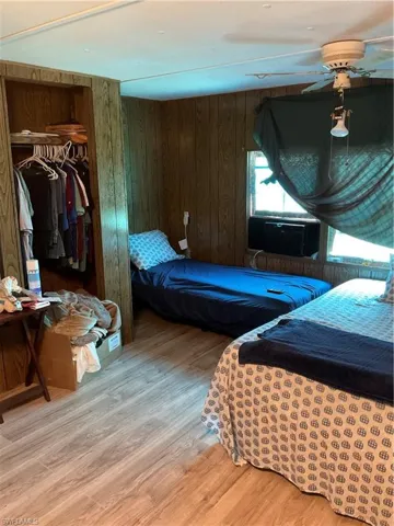 Bedroom with laminate flooring, a closet, and panel walls