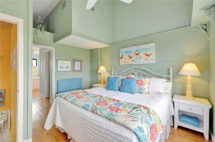 Bedroom featuring wooden walls, wood finished floors, a ceiling fan, and a high ceiling