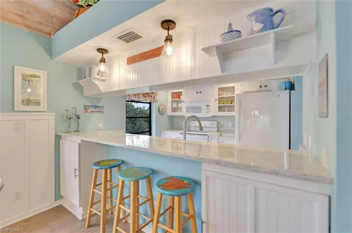 Kitchen featuring white cabinets, white appliances, decorative light fixtures, open shelves, and glass fronted cabinets