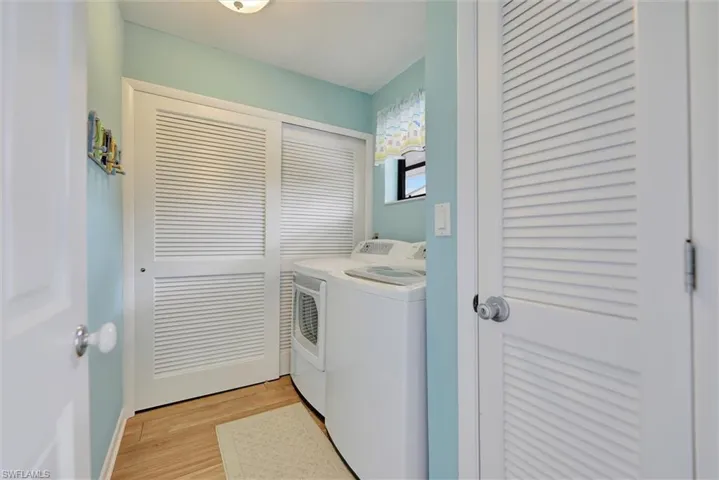 Laundry room with light wood finished floors and washer and clothes dryer