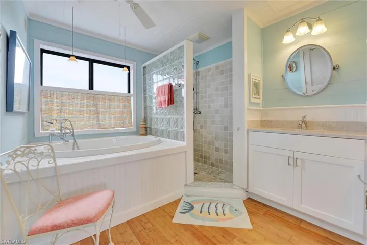 Full bath with a bath, a walk in shower, vanity, light wood-style floors, and crown molding