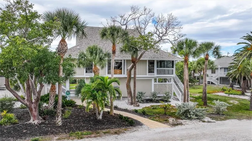 Raised beach house featuring roof with shingles and a balcony