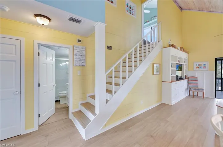 Staircase featuring wood finished floors, a high ceiling, wooden walls, and healthy amount of natural light