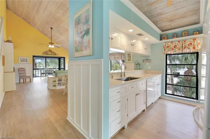 Kitchen with a vaulted wood ceiling, white cabinetry, ceiling fan, light wood-style floors, and white dishwasher