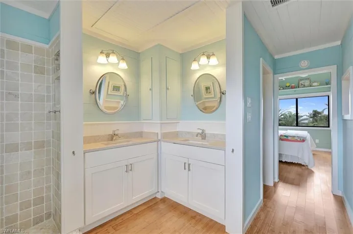 Ensuite bathroom with light wood finished floors, ornamental molding, and vanity