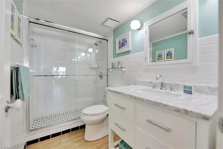 Bathroom featuring vanity, a shower stall, tile walls, and light wood-style floors