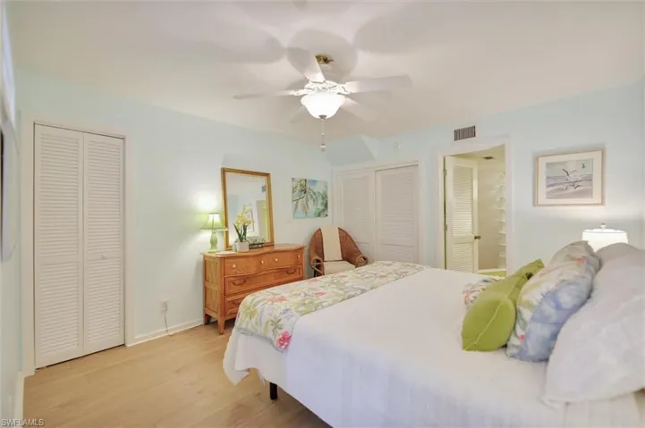 Bedroom featuring multiple closets, light wood-type flooring, and a ceiling fan