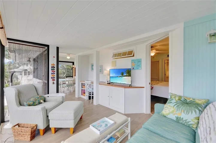 Living area with a ceiling fan, wood finished floors, and expansive windows