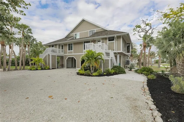 View of front of property featuring a carport, driveway, a shingled roof, and a balcony
