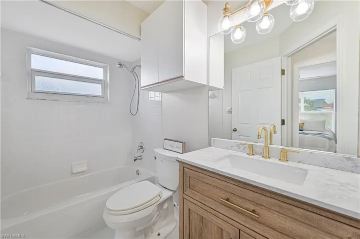 Bathroom with light marble finish floors, two vanities, tiled shower, and a chandelier