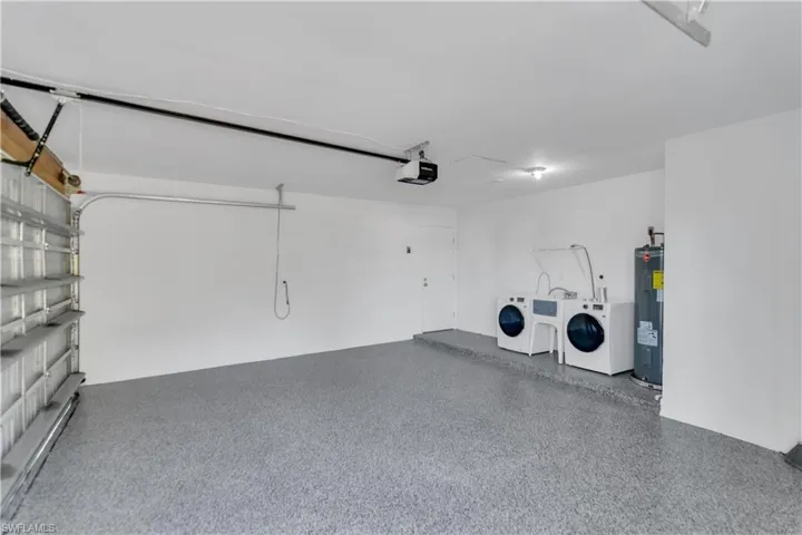 Garage with a garage door opener, water heater, and washing machine and clothes dryer