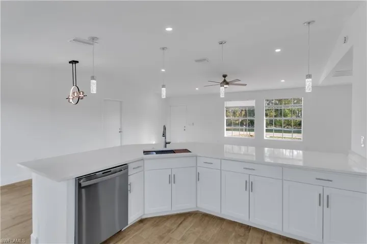Kitchen featuring light wood-style flooring, a sink, stainless steel dishwasher, white cabinets, and light countertops