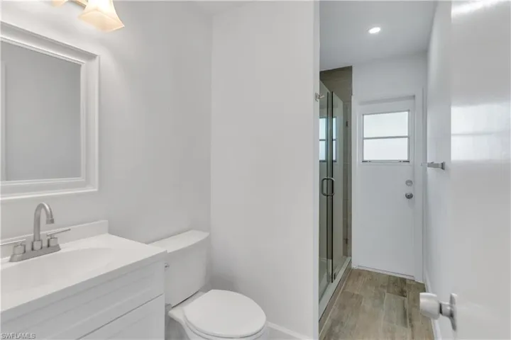 Bathroom with a stall shower, toilet, vanity, and wood finished floors